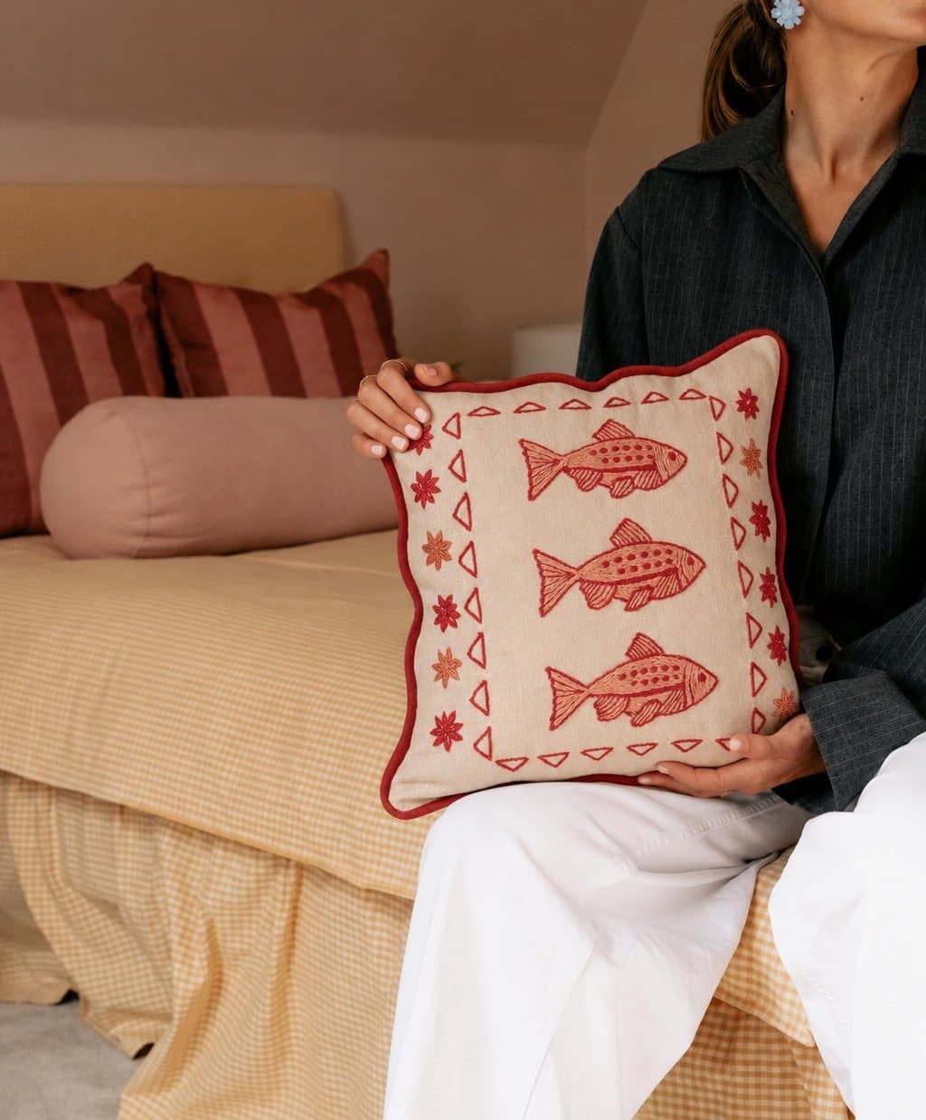 The Three Fish Cushion held on a bed